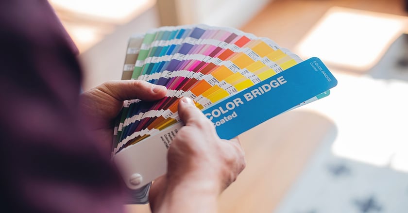 Hands hold open color sample fan in office