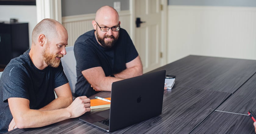 Two Vye team members sit at desk looking at computer