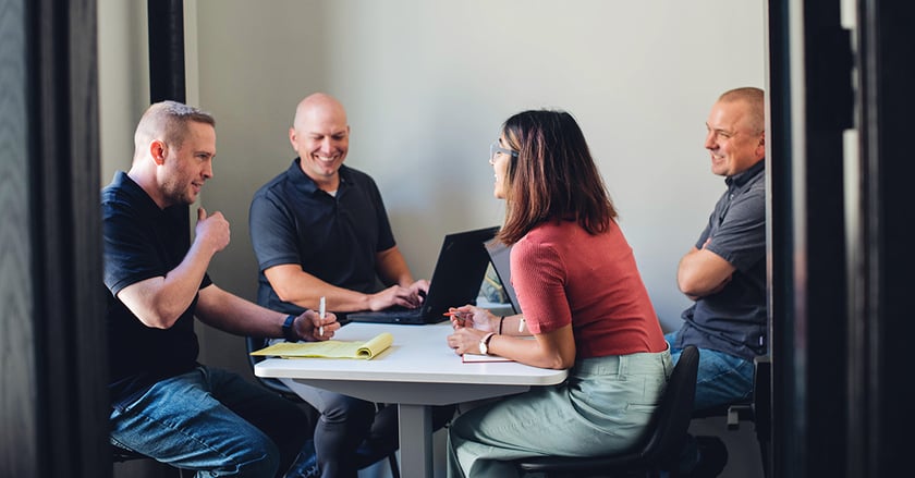 Vye Team members laugh while sitting at table with laptops