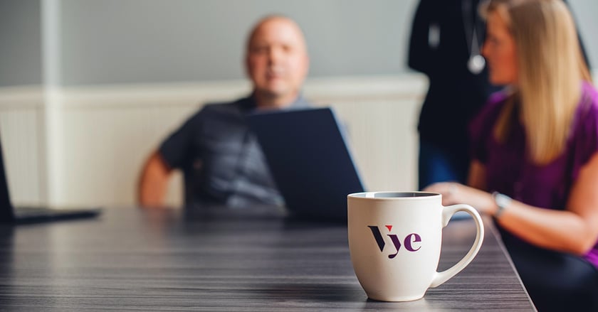 Vye mug sits on conference room desk with team in background