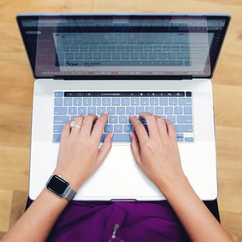 Hands typing on a laptop