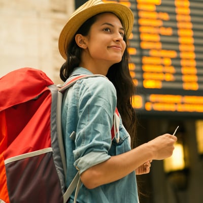 Young woman with backpack holds plane ticket in airport