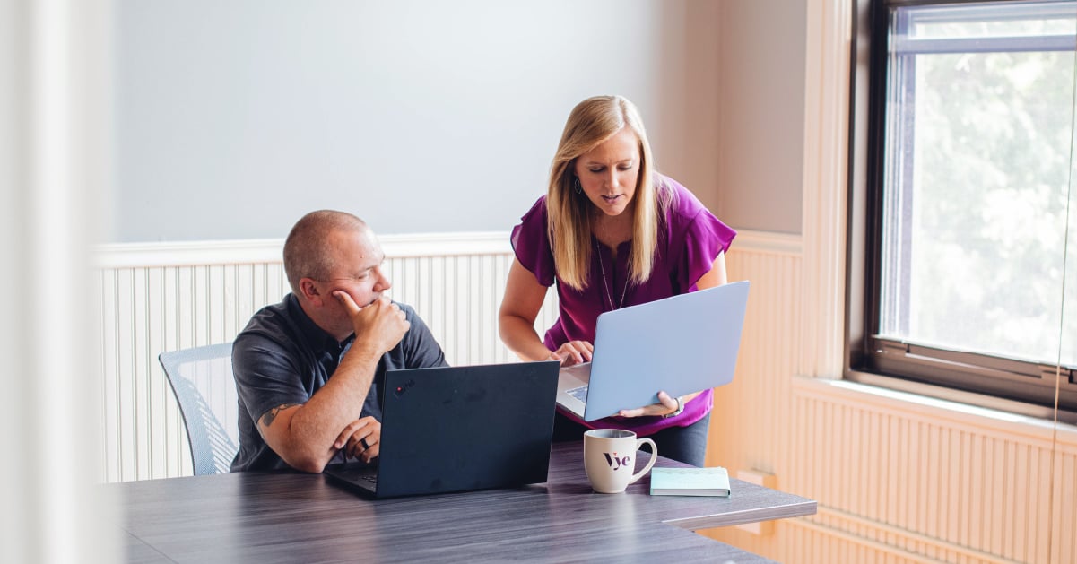Two Vye team members on laptops work on bank marketing strategy