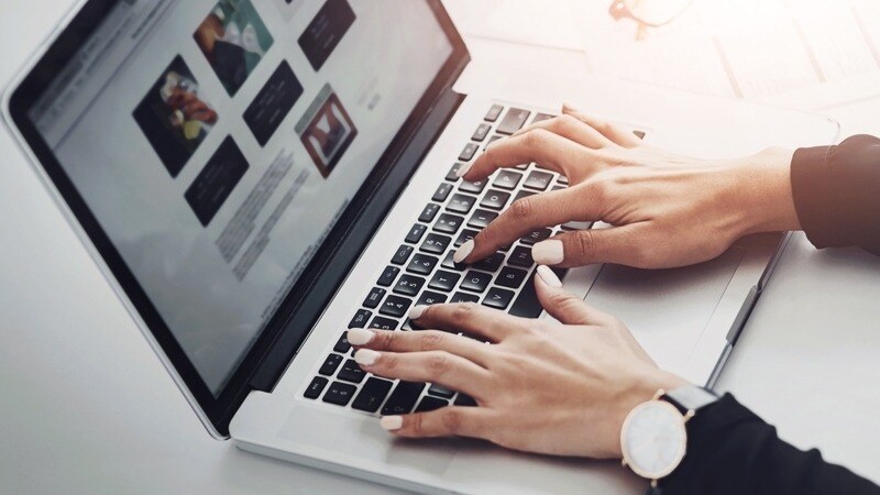 Hands type website copy into wireframe on laptop screen