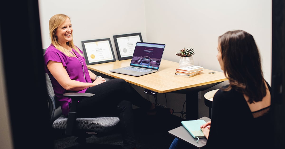 Vye Agency Employees smiling and discussing at a desk