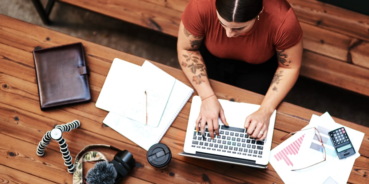 Woman working on computer with papers on desk
