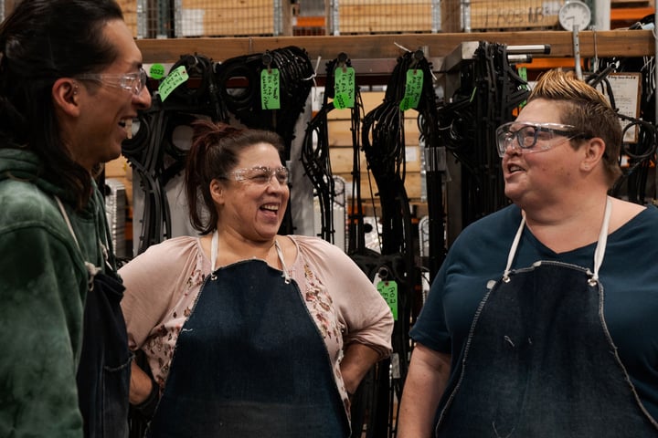 AGC team laughs while talking in manufacturing plant.
